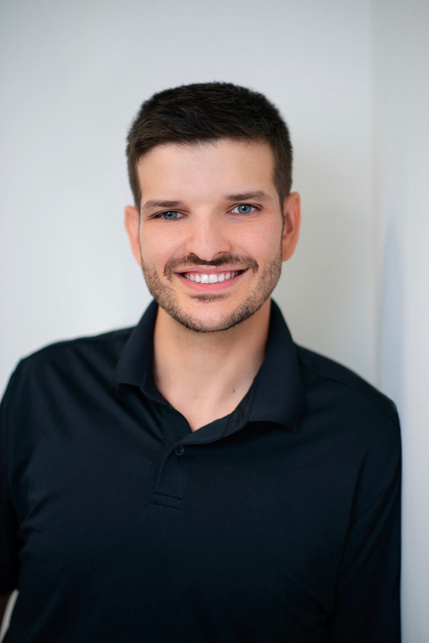 Smiling man in black polo shirt.