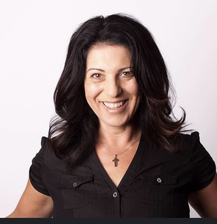 Smiling woman with black hair and necklace.