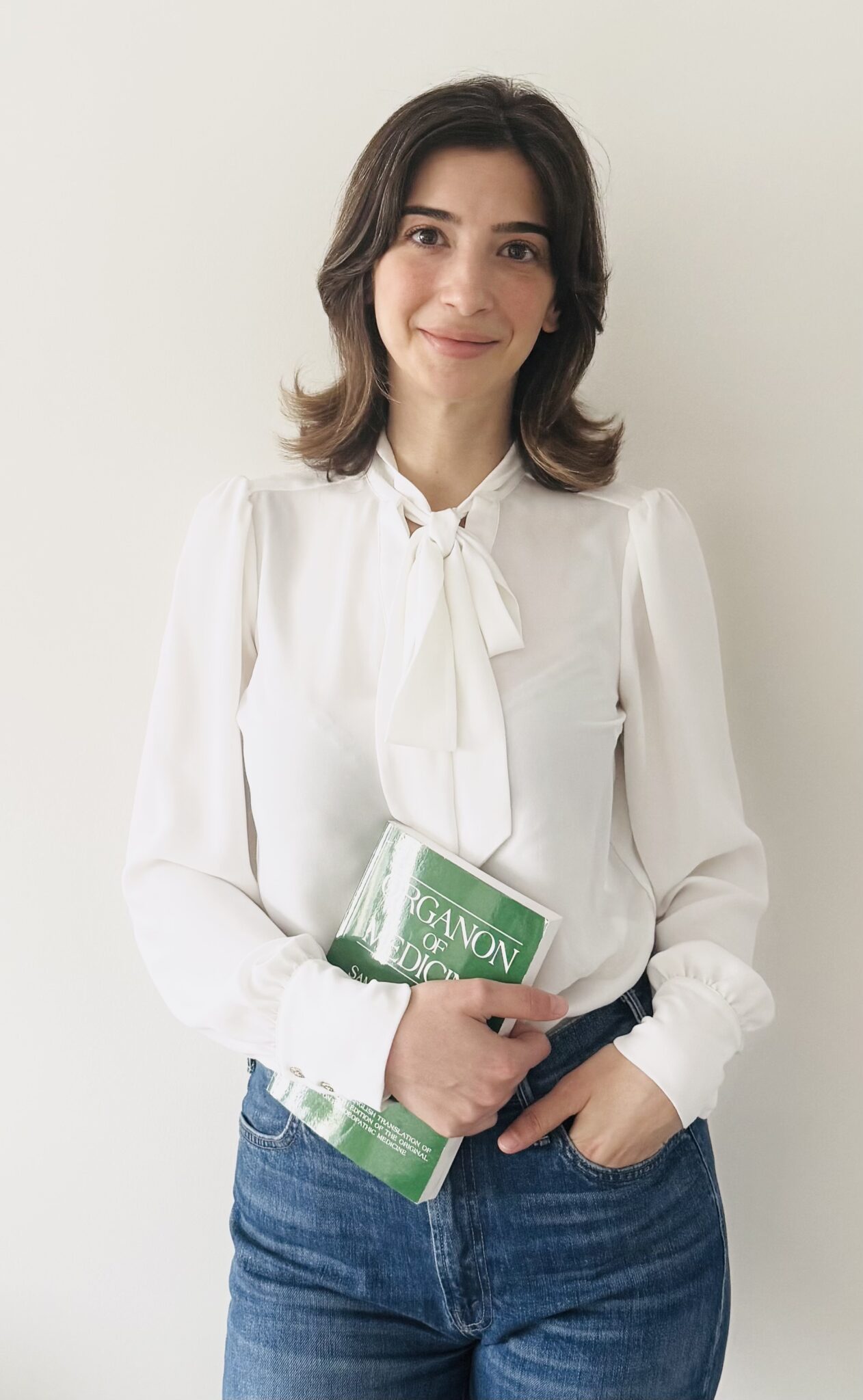 Woman in white blouse holding a book.