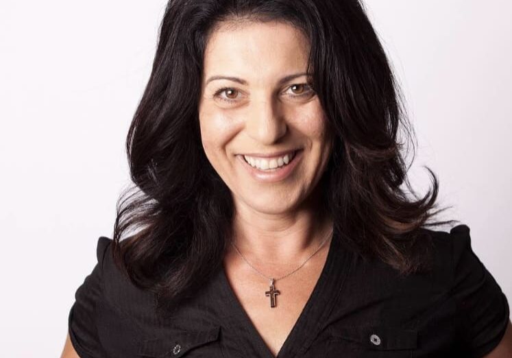 Smiling woman with black hair and necklace.