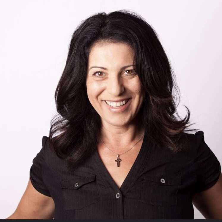 Smiling woman with black hair and necklace.