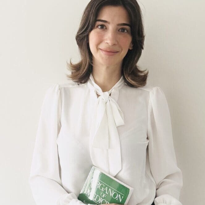 Woman in white blouse holding a book.