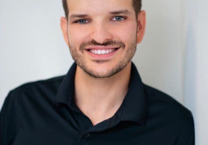 Smiling man in black polo shirt.