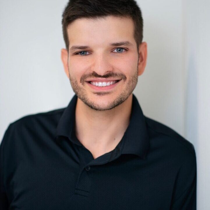 Smiling man in black polo shirt.