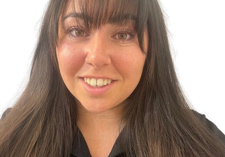 Here's a short alt tag for the image: Smiling woman with long brown hair.