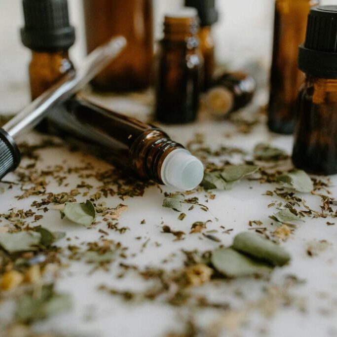Essential oil bottles with dried herbs scattered.